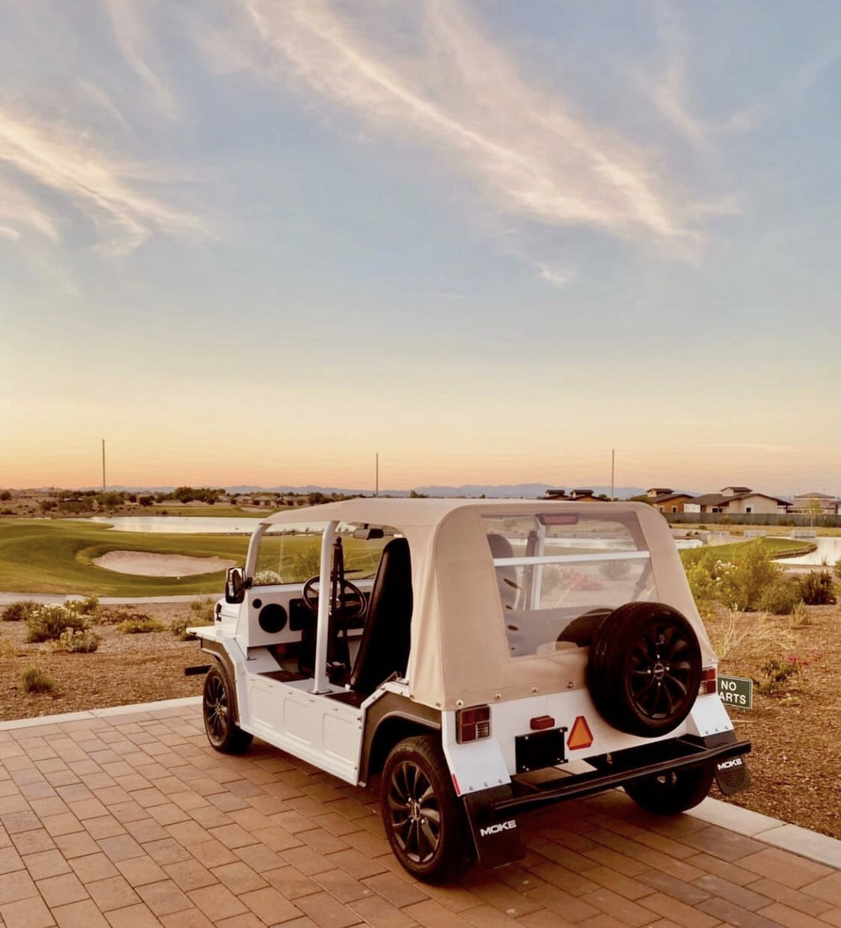 A cream Moke parked beside an Arizona golf course at sunset
