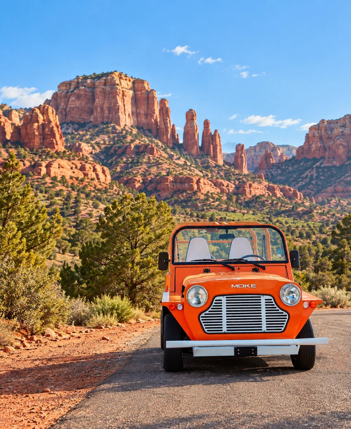 An orange Moke parked on a road below the red rock buttes of Sedona