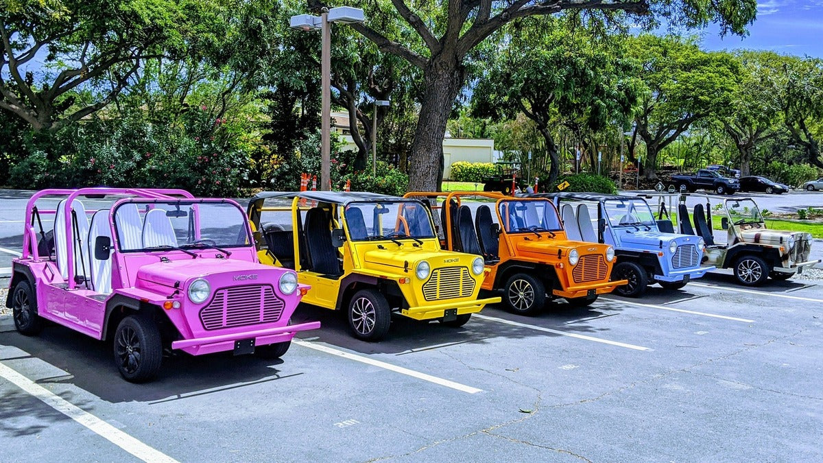Five Mokes in pink, yellow, orange, blue and cream parked in a row