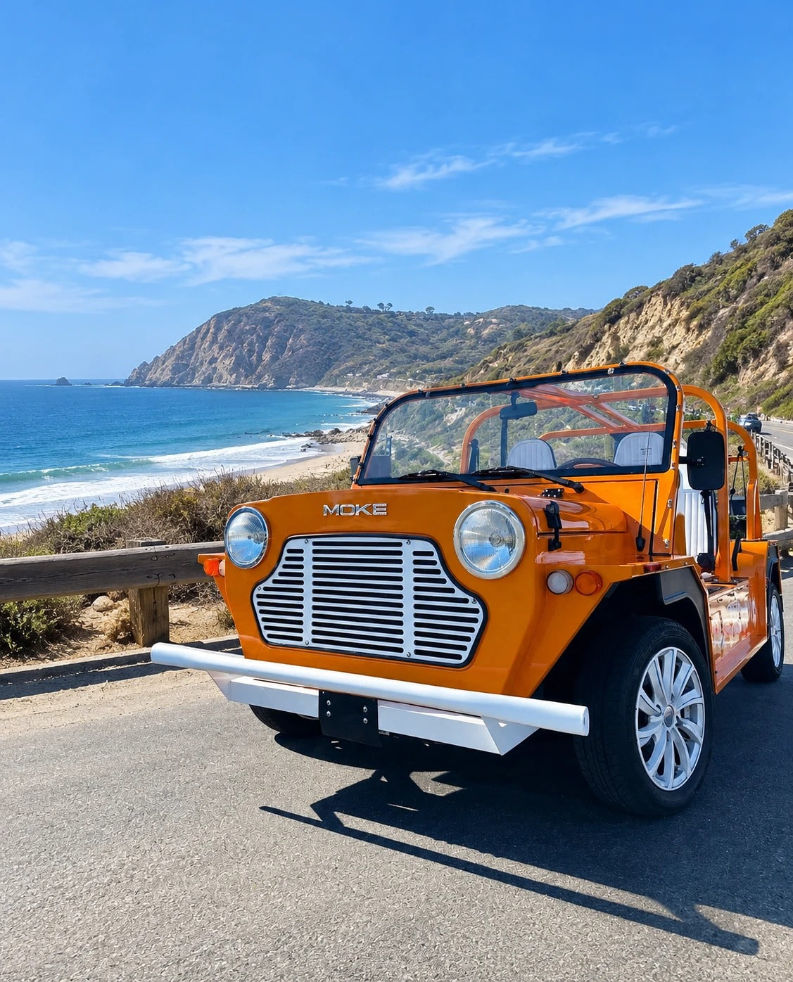 An orange Moke on the Pacific Coast Highway below the Point Dume headland