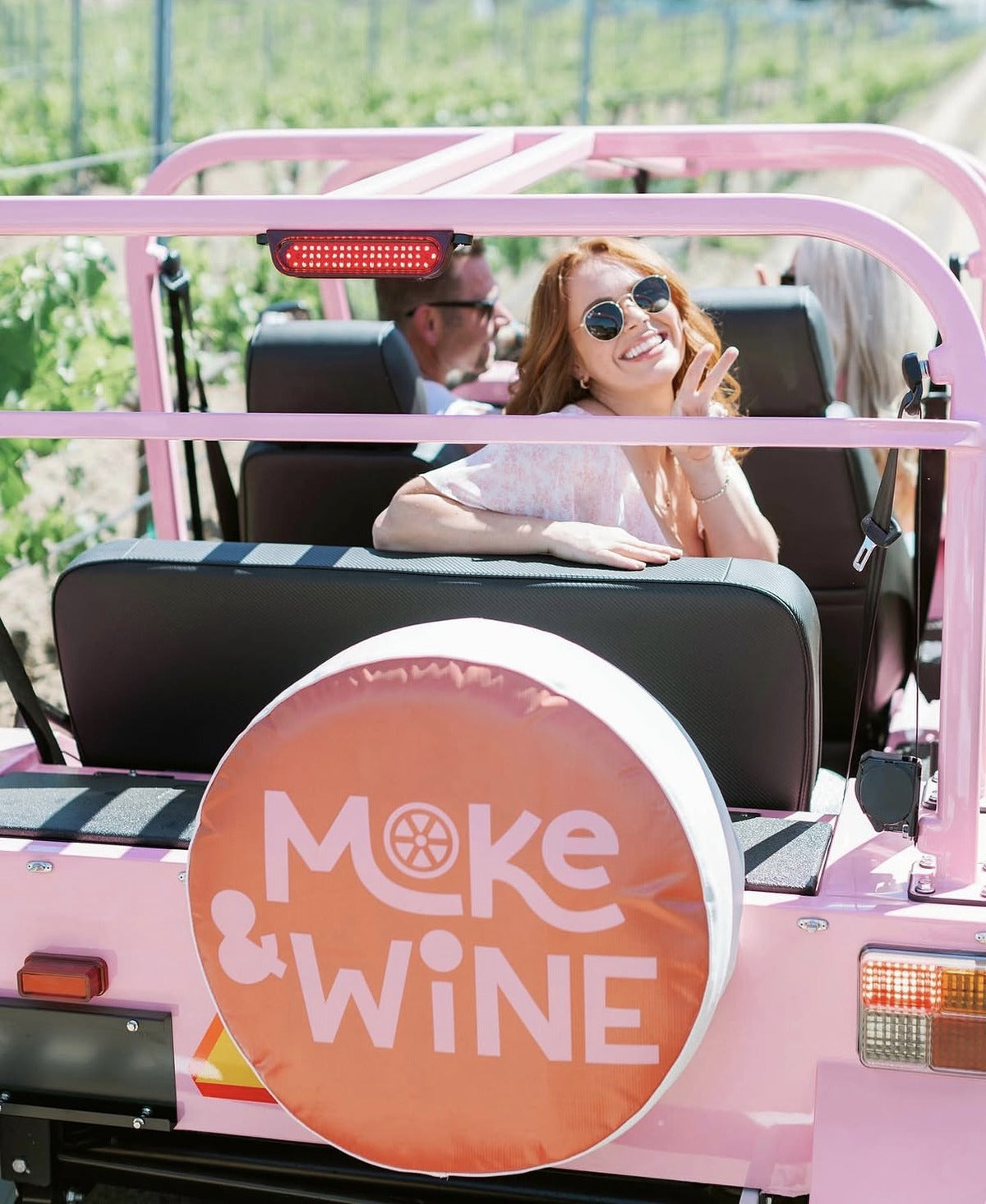 A couple in a pink Moke with a Moke and Wine spare wheel cover